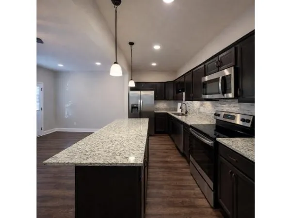 a kitchen with kitchen island granite countertop stainless steel appliances and view of living room