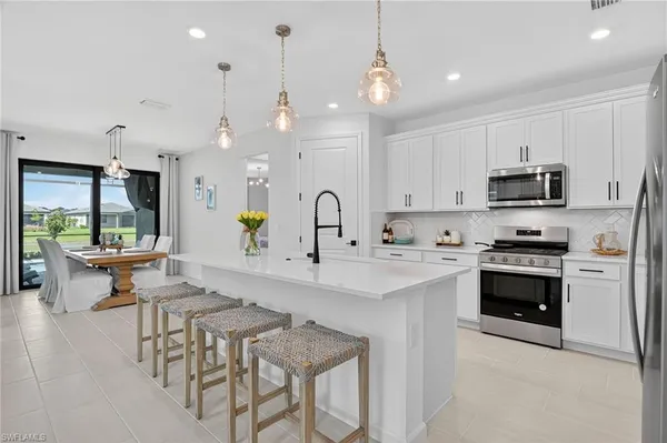 a kitchen with stainless steel appliances kitchen island a white cabinets and a chandelier