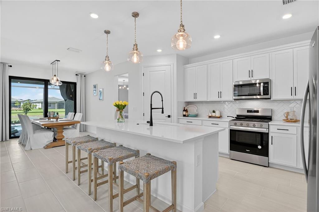 1953 Fresno Avenue Naples, FL 34120 - Photo 3 of 33 a kitchen with stainless steel appliances kitchen island a white cabinets and a chandelier