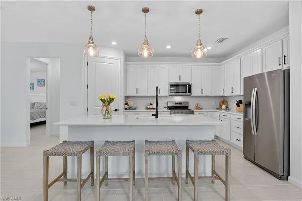 a kitchen with stainless steel appliances kitchen island granite countertop a refrigerator a stove a sink a dining table and chairs