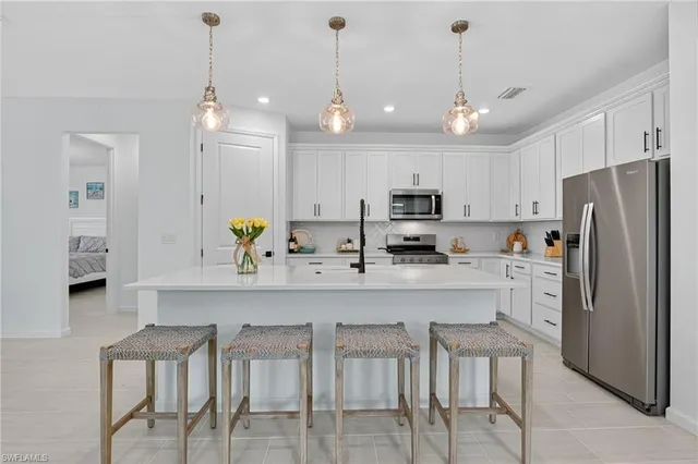 a kitchen with stainless steel appliances kitchen island granite countertop a refrigerator a stove a sink a dining table and chairs