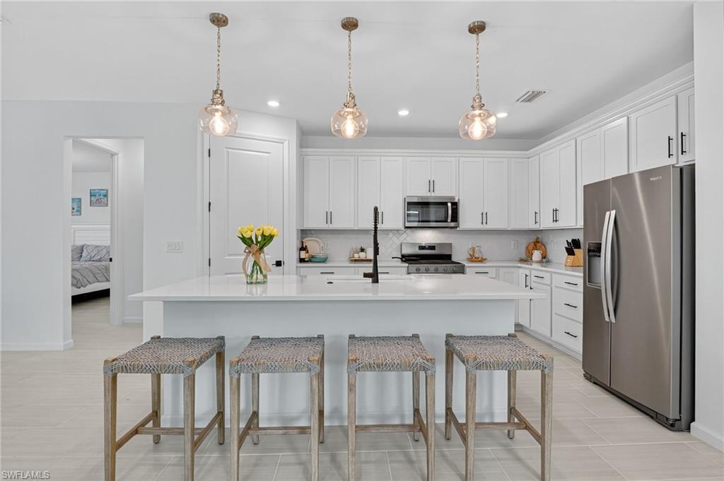 1953 Fresno Avenue Naples, FL 34120 - Photo 4 of 33 a kitchen with stainless steel appliances kitchen island granite countertop a refrigerator a stove a sink a dining table and chairs