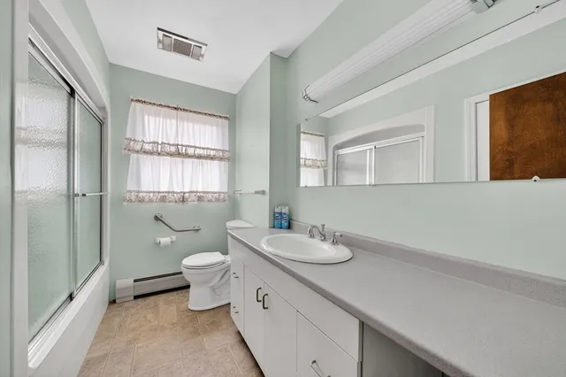 a bathroom with a granite countertop toilet sink and mirror