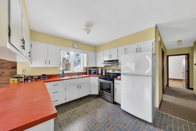 a kitchen with stainless steel appliances a refrigerator sink and white cabinets
