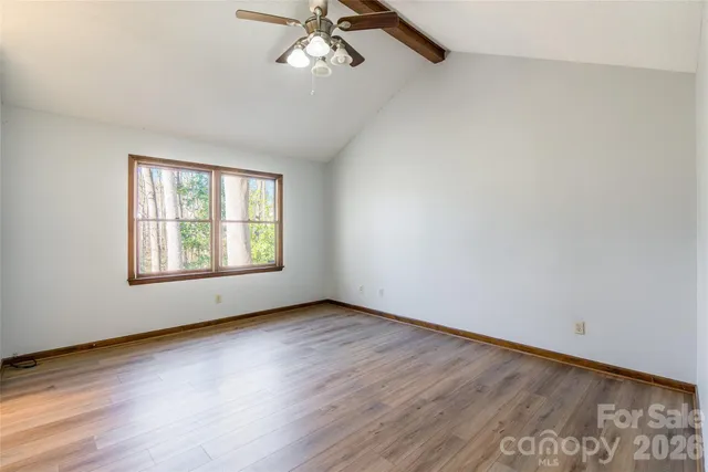 an empty room with wooden floor chandelier fan and windows
