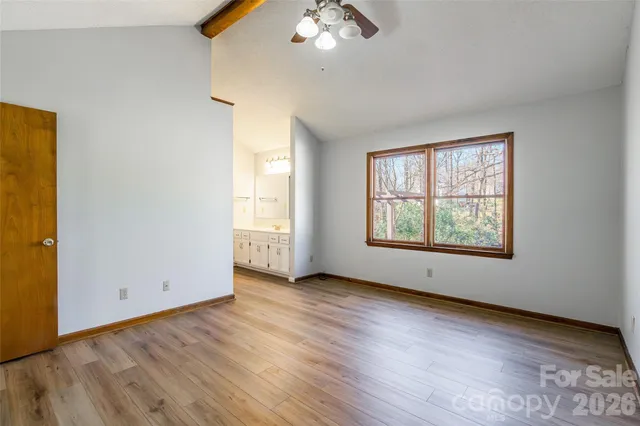 an empty room with wooden floor chandelier and windows