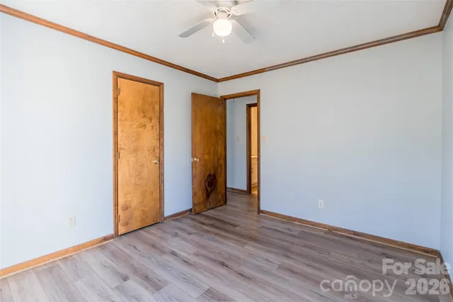 an empty room with wooden floor and a ceiling fan