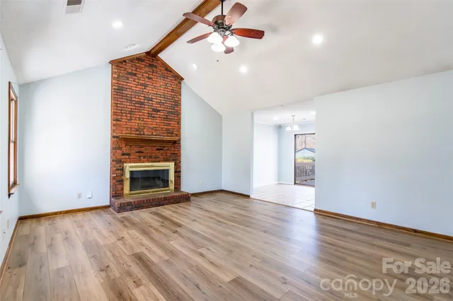 an empty room with wooden floor ceiling fan and windows