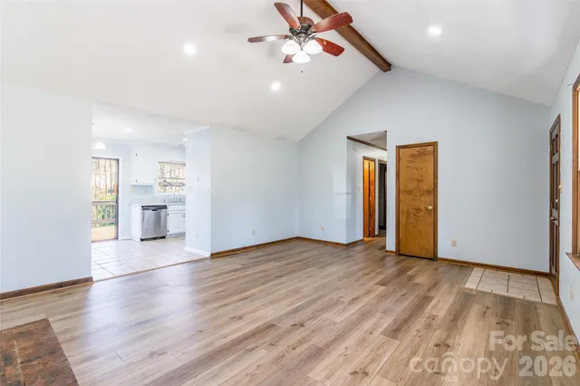 a view of an empty room with window and wooden floor