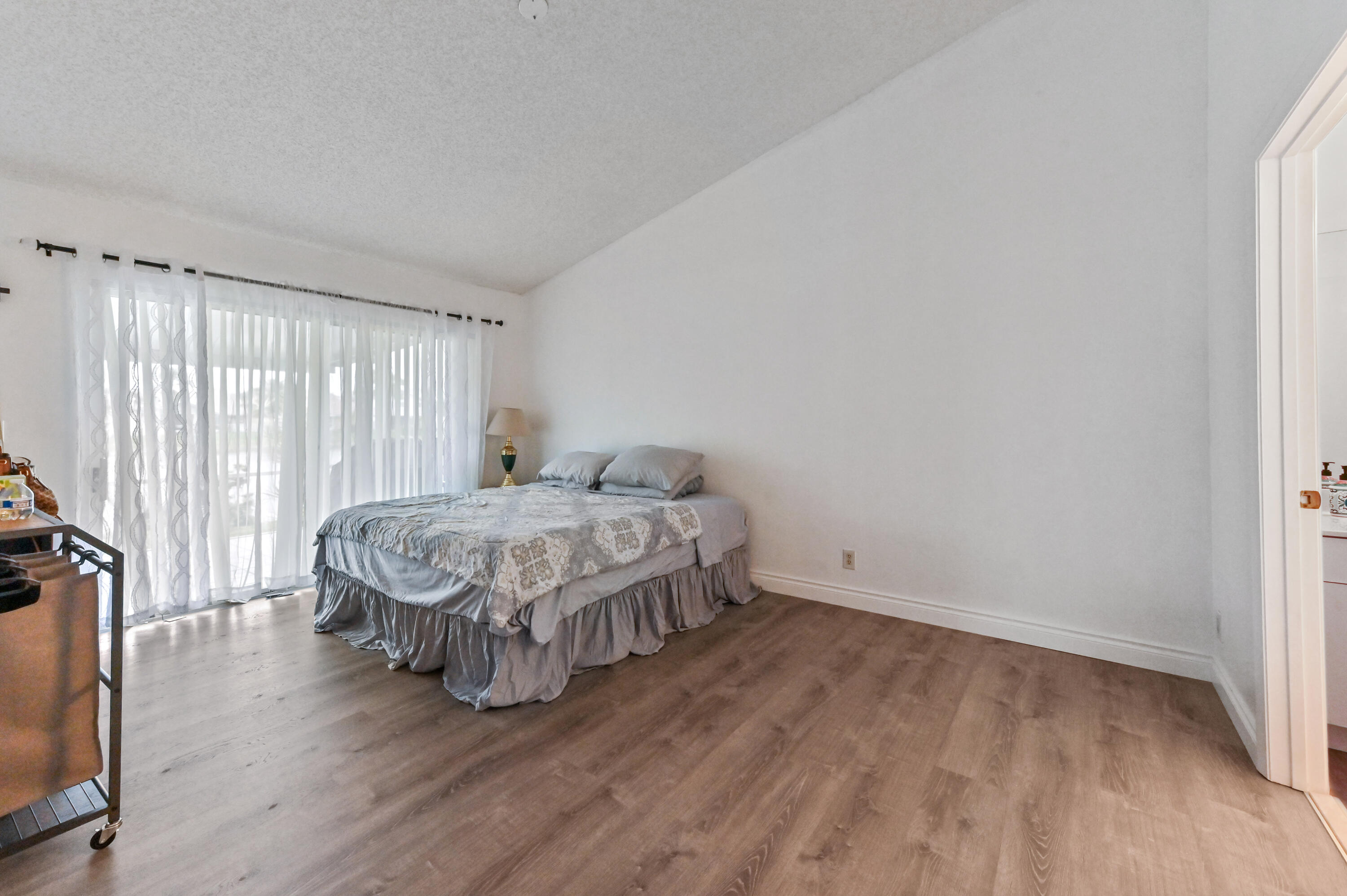 7433 Shell Ridge Terrace Lake Worth, FL 33467 - Photo 20 of 45 a spacious bedroom with a bed and wooden floor