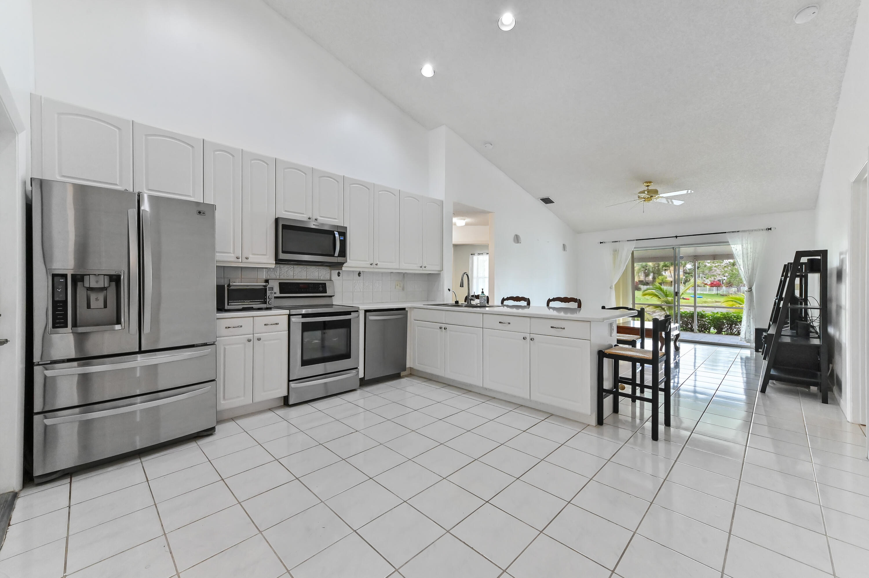 7433 Shell Ridge Terrace Lake Worth, FL 33467 - Photo 8 of 45 a kitchen with white cabinets and stainless steel appliances