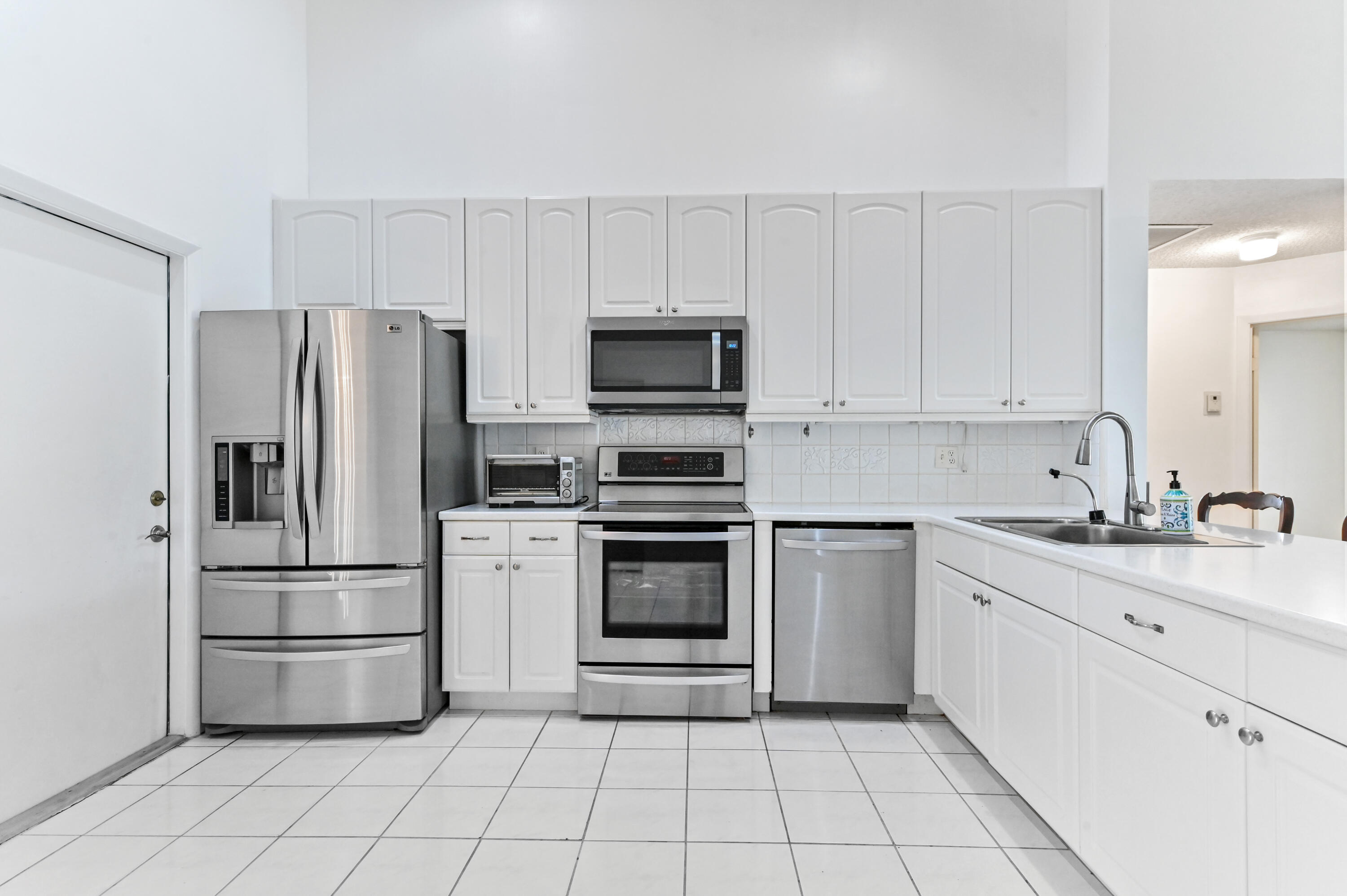 7433 Shell Ridge Terrace Lake Worth, FL 33467 - Photo 9 of 45 a kitchen with white cabinets and stainless steel appliances