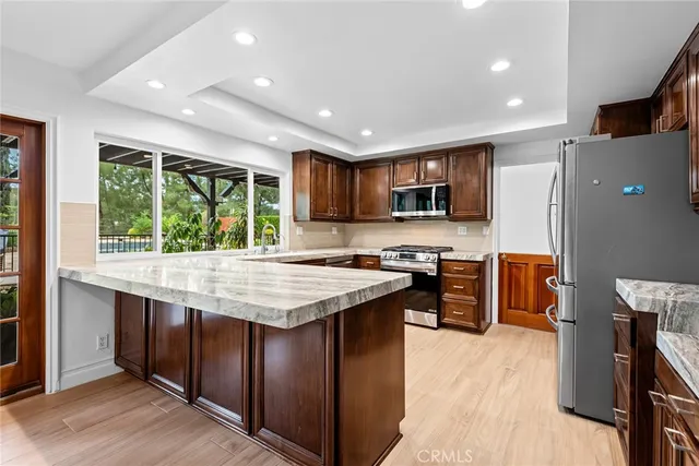 a kitchen with stainless steel appliances granite countertop wooden cabinets a stove top oven a sink and dishwasher a refrigerator with wooden floor
