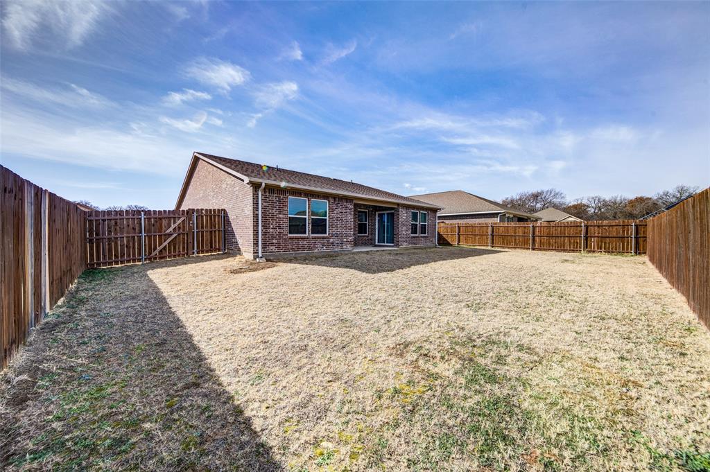 905 Avagail Avenue Springtown, TX 76082 - Photo 26 of 26 Rear view of house with brick siding, a patio, and a fenced backyard