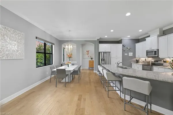 a very nice looking dining room with kitchen island furniture a large window and a wooden floor