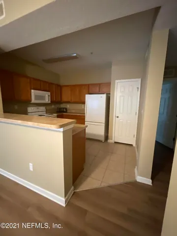 a view of a kitchen with refrigerator and wooden floor