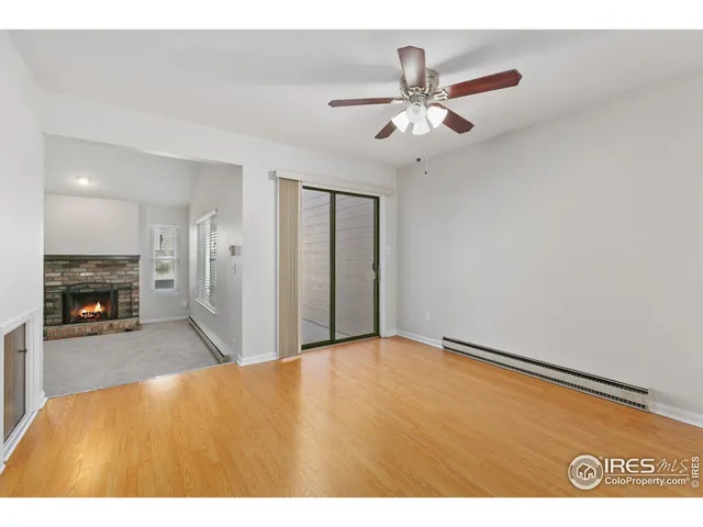 a view of an empty room and kitchen with fireplace