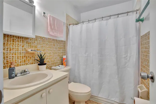 a bathroom with a sink a toilet and shower curtain