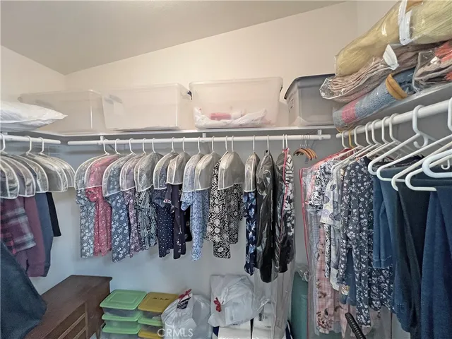 a view of walk in closet with clothes and shoes