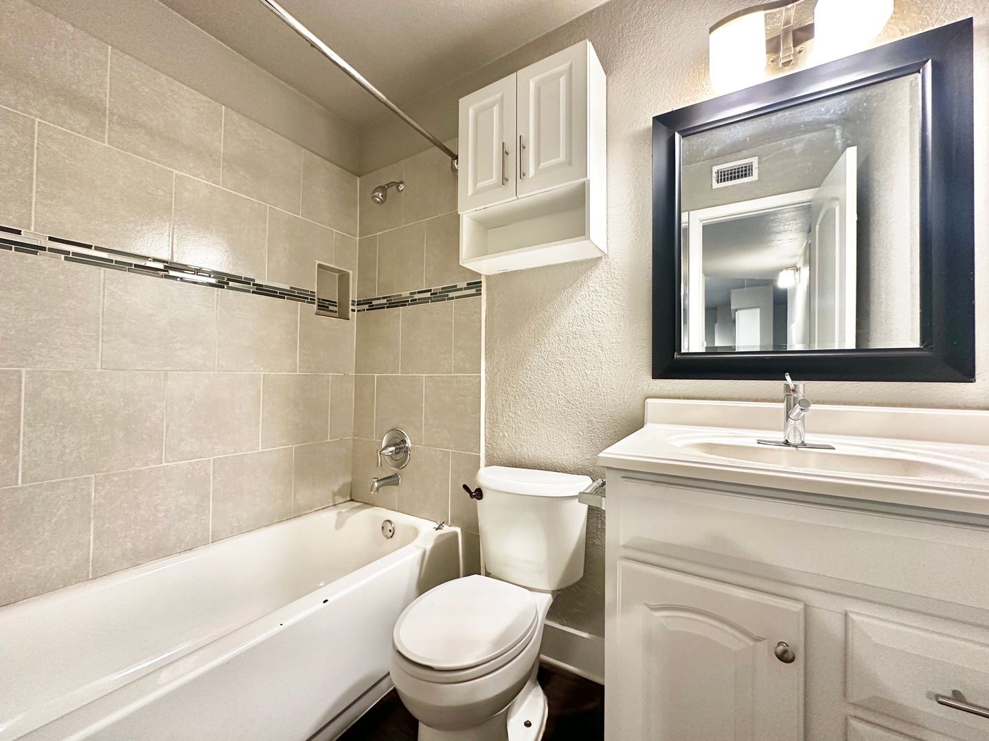4316 Bull Creek Road, Unit 107 Austin, TX 78731 - Photo 7 of 8 Bathroom featuring a white bathtub, tiled shower surround with a decorative accent band, and a vanity with a white countertop and sink