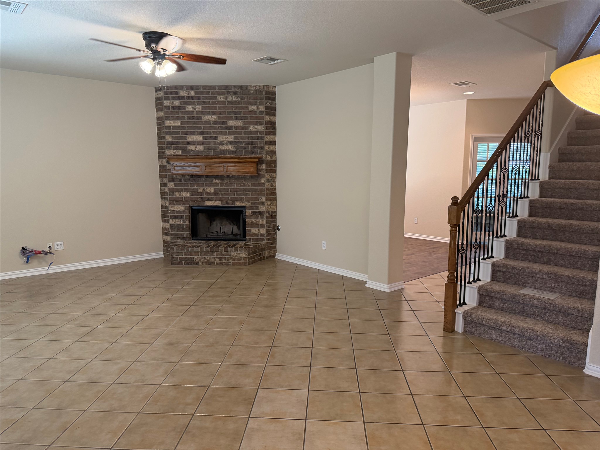 3021 Grand Mission Way Pflugerville, TX 78660 - Photo 10 of 31 A corner brick fireplace grounds this spacious living area with tile flooring and an inviting staircase.