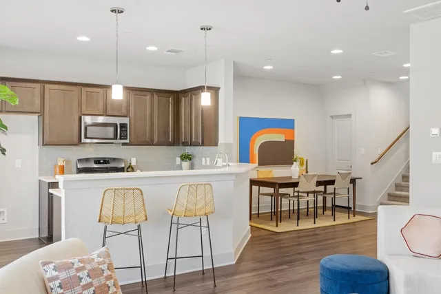 a kitchen with stainless steel appliances granite countertop a stove top oven a sink dishwasher a dining table and chairs with wooden floor