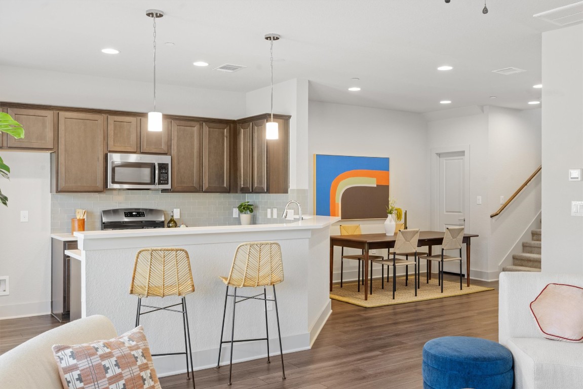 2056 Local Rebel Street Leander, TX 78641 - Photo 8 of 39 a kitchen with stainless steel appliances granite countertop a stove top oven a sink dishwasher a dining table and chairs with wooden floor