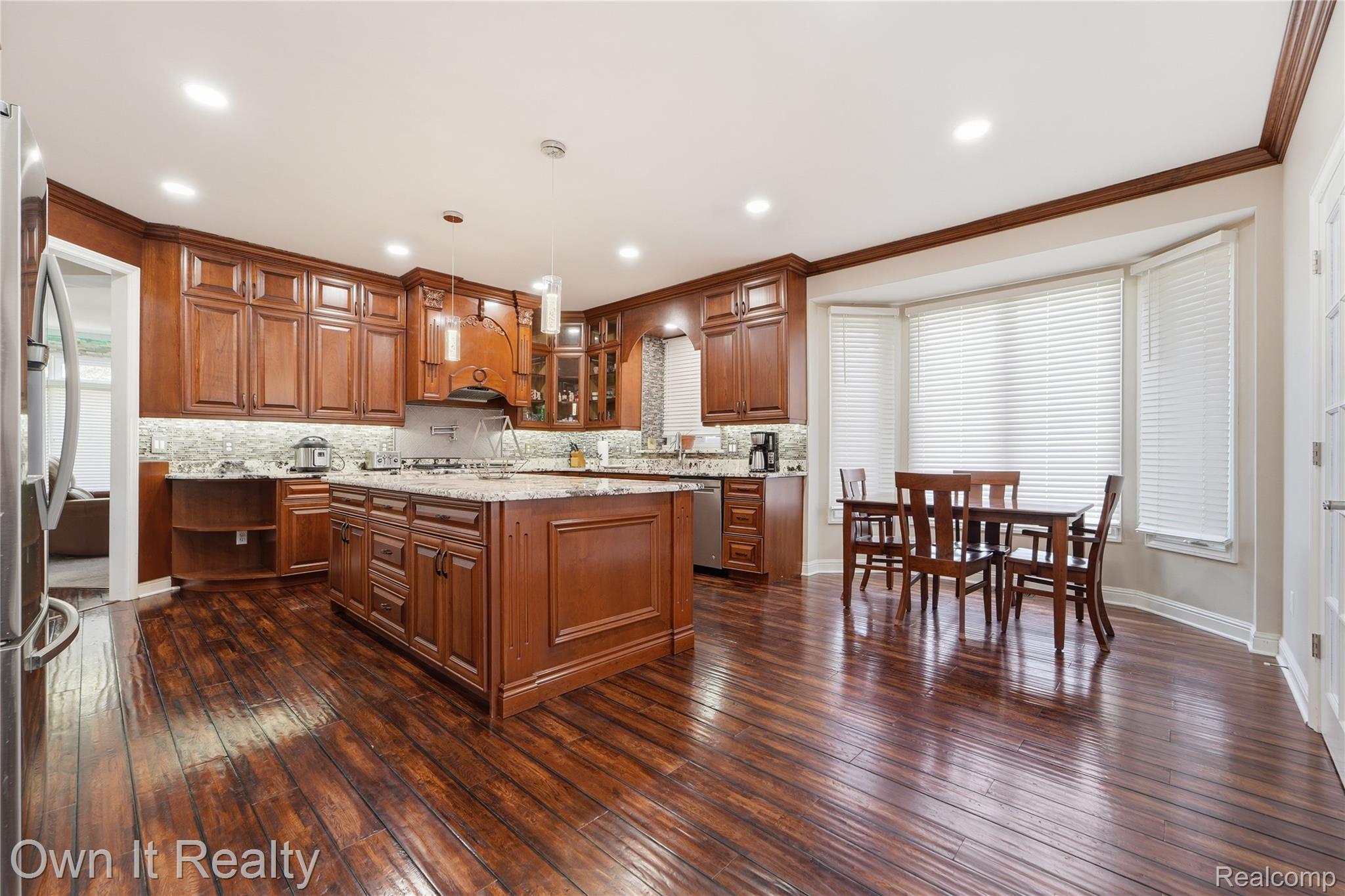 48280 Gladstone Road Canton, MI 48188 - Photo 22 of 59 Spacious kitchen featuring rich wood cabinetry, wood-finish flooring, a central island with a cooktop, granite countertops, and a bay window