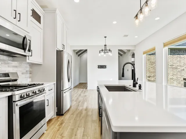a kitchen with stainless steel appliances kitchen island a stove a sink and a refrigerator