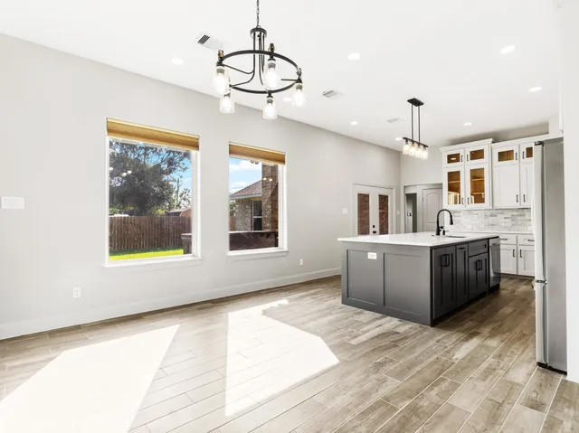 a kitchen with stainless steel appliances granite countertop a stove a sink dishwasher a refrigerator and a dining table with wooden floor