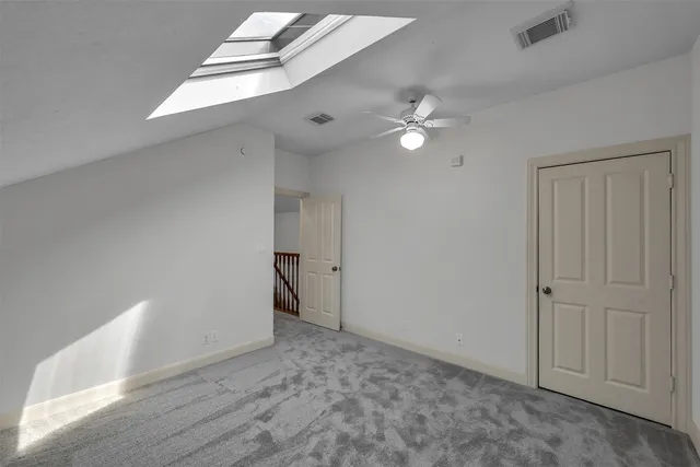 a view of a hallway with wooden floor and a bathroom