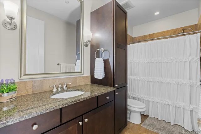 a bathroom with a granite countertop sink toilet and shower