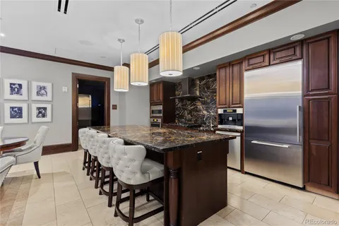 a kitchen with stainless steel appliances granite countertop a refrigerator a sink a stove and a dining table with wooden floor