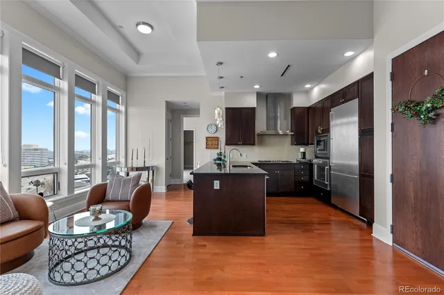 a large living room with stainless steel appliances kitchen island granite countertop a refrigerator a sink dishwasher a dining table and chairs with wooden floor