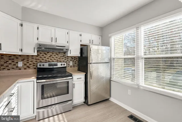 a kitchen with refrigerator a stove and white cabinets