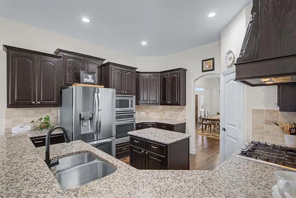 a kitchen with stainless steel appliances kitchen island granite countertop a refrigerator and a sink