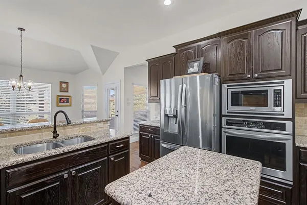 a kitchen with stainless steel appliances kitchen island granite countertop a refrigerator stove and sink