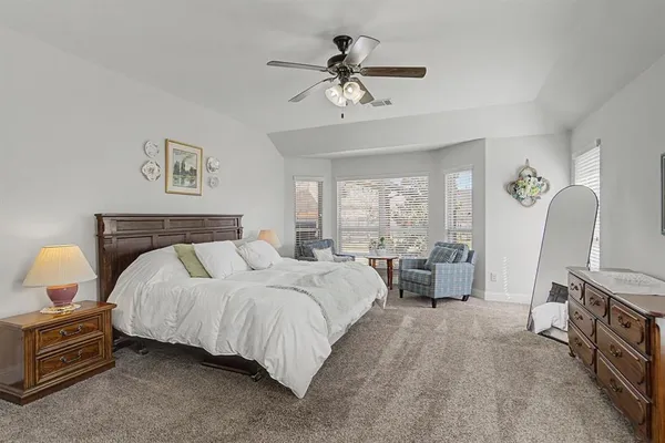 a spacious bedroom with a bed a couch and a chandelier