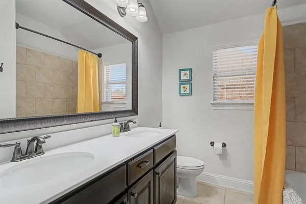 a bathroom with a double vanity sink toilet and a mirror