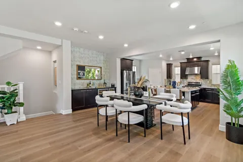 a kitchen with stainless steel appliances granite countertop wooden floor a stove top oven a sink dishwasher a dining table and chairs with wooden floor