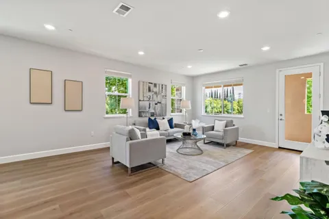 a living room with furniture kitchen view and a wooden floor