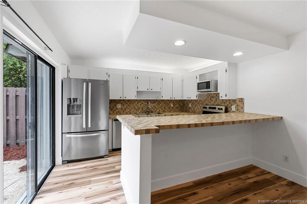 762 Northwest 10th Terrace Stuart, FL 34994 - Photo 16 of 41 a kitchen with kitchen island granite countertop a refrigerator and a sink