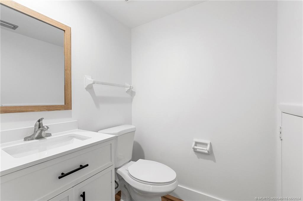 762 Northwest 10th Terrace Stuart, FL 34994 - Photo 22 of 41 a bathroom with a toilet a sink a mirror and vanity