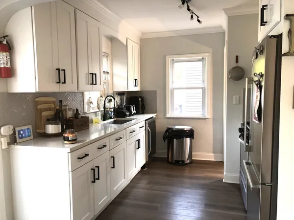 a kitchen with stainless steel appliances granite countertop a refrigerator a stove a sink and white cabinets