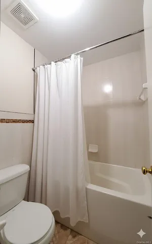 a white toilet sitting next to a bath tub