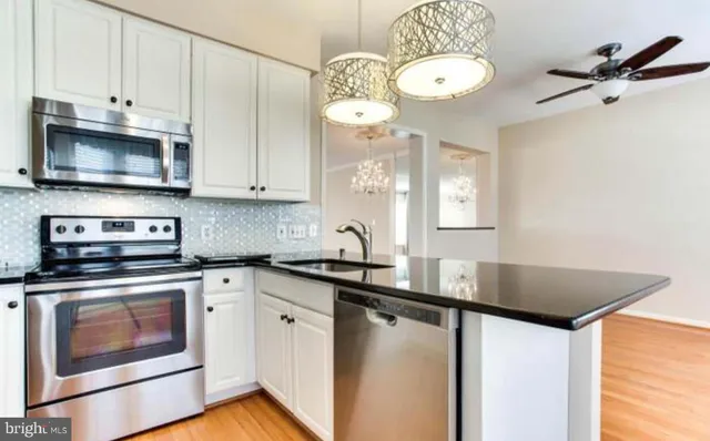 a kitchen with stainless steel appliances granite countertop a sink a stove and cabinets