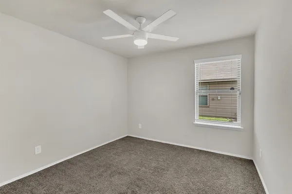 an empty room with a window and a ceiling fan