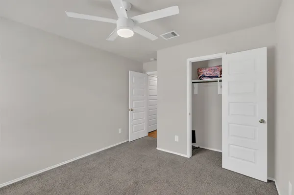 an empty room with closet and a ceiling fan