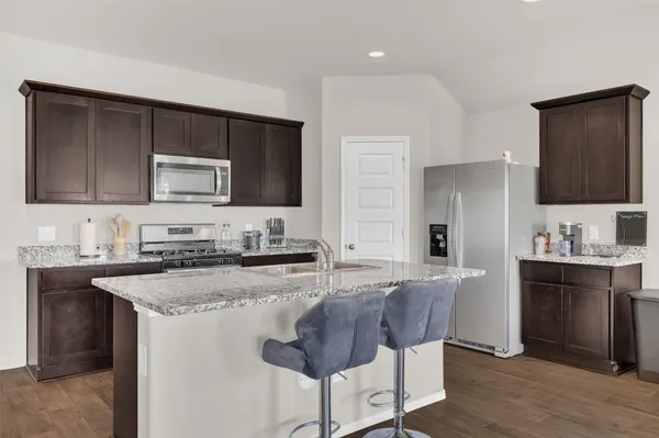 a kitchen with stainless steel appliances granite countertop a stove a sink a microwave a refrigerator and a stove