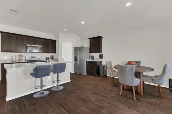 a kitchen with a dining table chairs and refrigerator